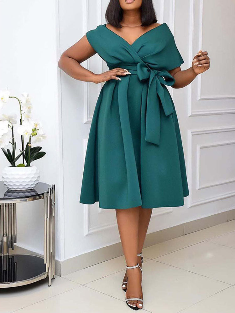 Woman standing with hands on hips, showcasing the front of a dark green A-line midi dress.