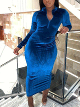A woman poses on stairs wearing a royal blue velvet midi dress with a quarter-zip neckline.