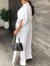 Side view of a woman in a white maxi dress, showcasing the side slit and sleeve detail.