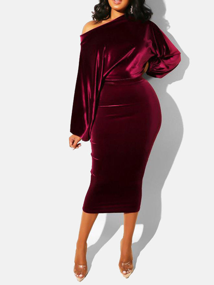 Full-body view of a woman in a red velvet off-the-shoulder midi dress with long sleeves, standing against a white background.