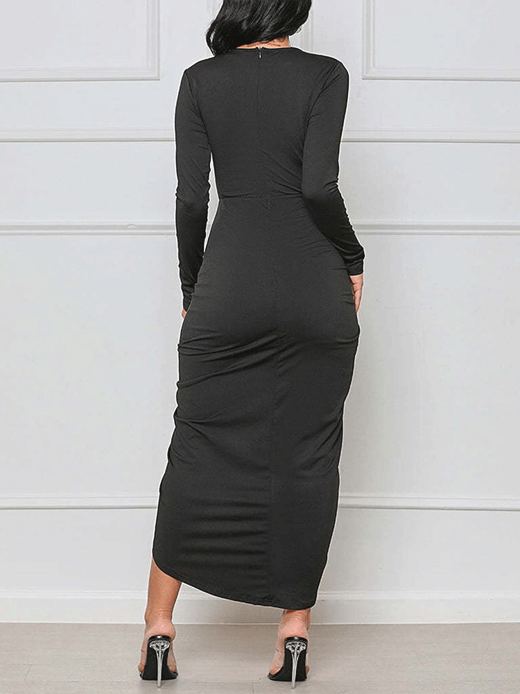 Back view of a woman wearing a black long-sleeve crop top and ruched midi skirt.