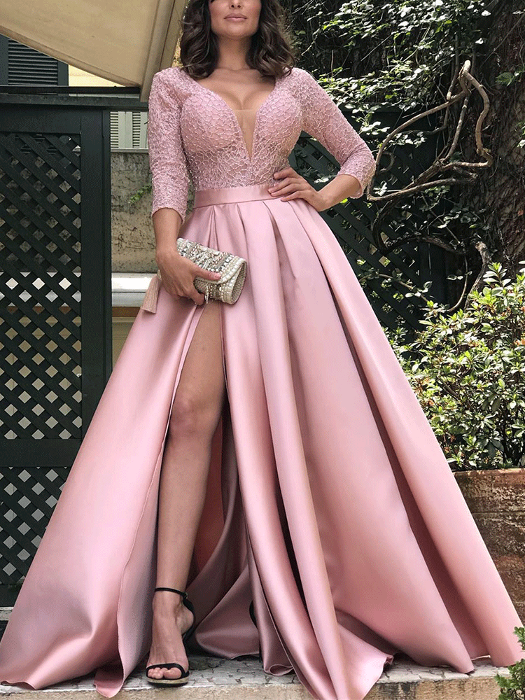 Woman wearing a pink formal gown with a V-neck, long sleeves, and a high slit.