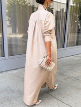 Back view of a woman wearing a long beige button-down shirt dress with blue jeans and beige high heels