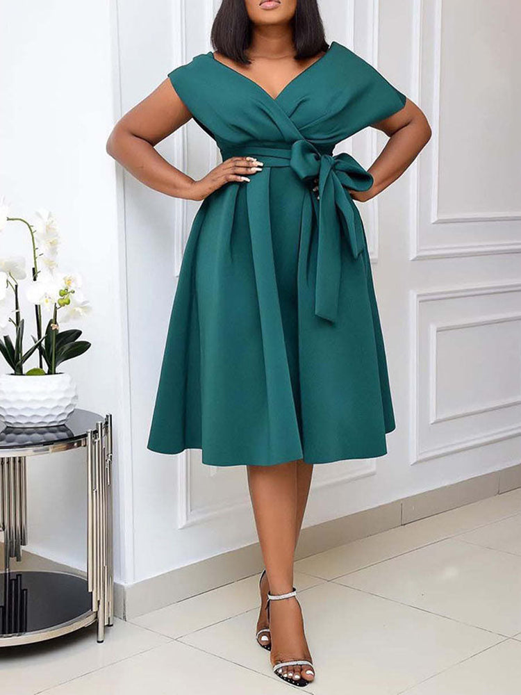 Woman posing with hands on hips, wearing a dark green A-line midi dress.
