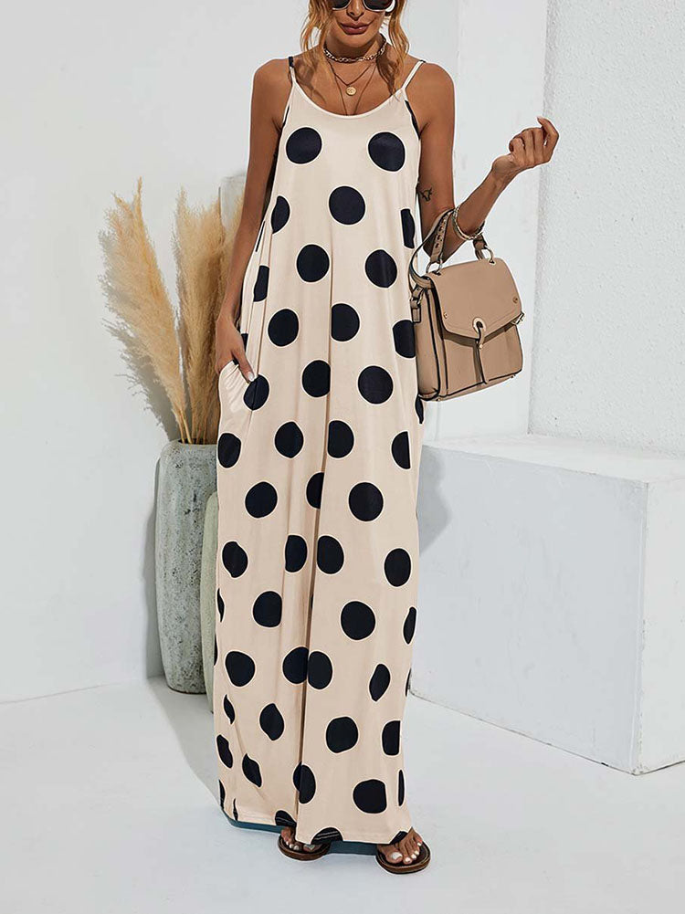 Woman wearing a beige polka dot maxi dress with spaghetti straps and pockets, standing in a room with decor, front view